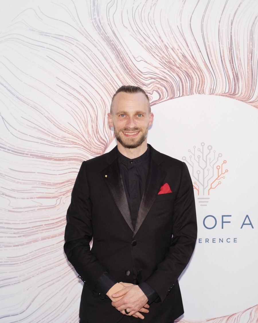 Fabian Westerheide im dunklen Anzug vor der Fotowand der Rise of AI