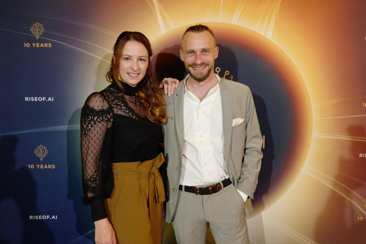 Veronika und Fabian Westerheide vor der Jubiläumswand der Rise of AI