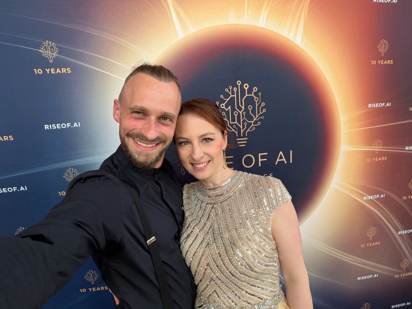 Veronika und Fabian Westerheide lächeln gemeinsam vor der Fotowand zu zehn Jahren Rise of AI